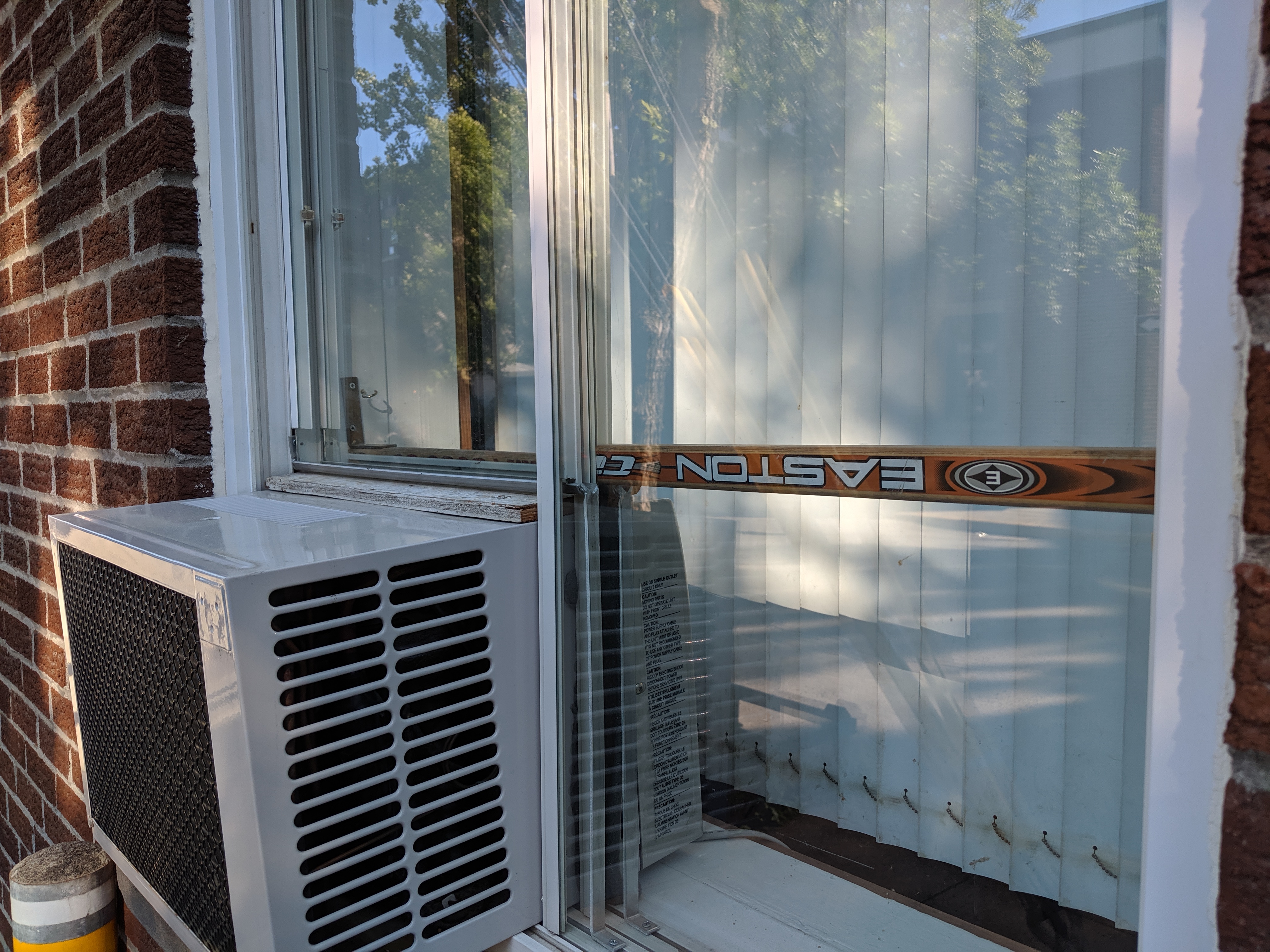 Hockey stick used as security bar in window with air conditioner